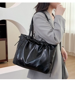 Vue latérale d'un grand sac cabas noir avec texture coulissante et cuir synthétique poli