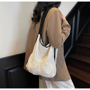 Detail of white hollow knit shoulder bag with contrasting black strap on brown suit