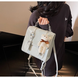 Detail of mint green glossy leather backpack with silver hardware and bear charm