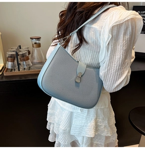 Detail of light blue crossbody bag featuring twill fabric texture and silver metal buckle