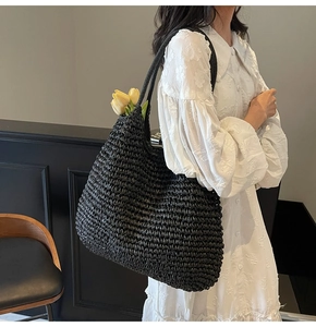 Detail of black woven straw tote bag with long straps and artistic tulip decoration