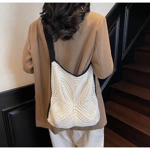 Detail of minimalist hollow knit shoulder bag with contrast black trim and wide strap