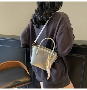 Detail of a silver metallic mini bucket bag with removable strap and decorative charms
