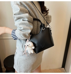 Sac seau noir avec breloque ours en peluche et texte embossé porté par mannequin