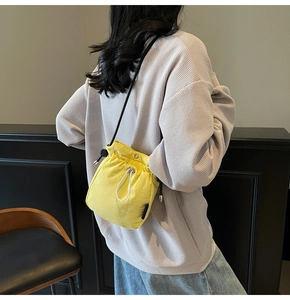 Model wearing a bright yellow drawstring bucket bag with a slim black shoulder strap