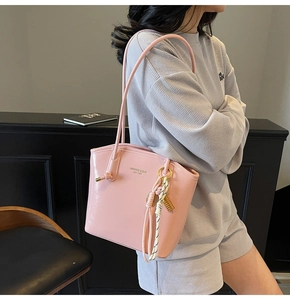 Dettaglio borsa tote rosa lucida con scritte dorate e nappa decorativa elegante