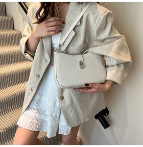 Close-up of ivory woven shoulder bag with silver metal buckle and detachable leather strap