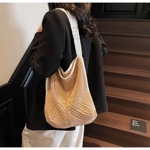 Detailed close-up of hollow knit tote bag with beige crochet texture and white straps