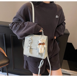 Detail of light blue PU leather backpack with double buckle flap and white bear charm
