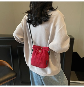 Rear view of a model wearing a red drawstring bucket bag with light waffle sweater