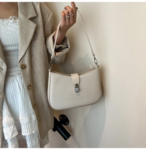 Detailed texture of cream woven shoulder bag with silver metallic buckle on khaki suit