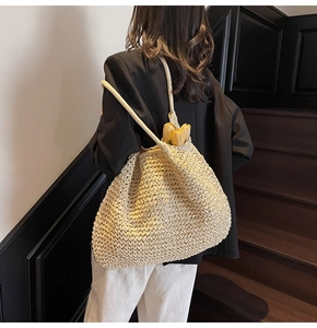 Gros plan détaillé d'un grand sac cabas beige en paille tressée avec une texture fine et fleur