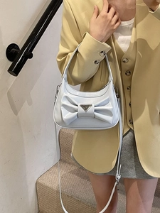 Fashionable light blue crossbody bag with large bow design and metal logo on a model