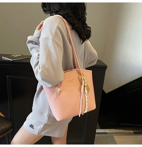 Dettaglio di una borsa tote rosa in pelle con nappina intrecciata e logo dorato inciso
