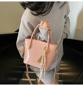 Detail of light pink glossy leather handbag with beaded handles and brand logo print