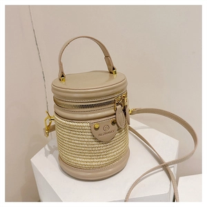 Dettaglio borsa a secchiello in paglia beige con finiture in pelle e hardware dorato