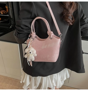 Gros plan détaillé d'un sac seau rose avec un porte-clé chien en peluche et un ruban