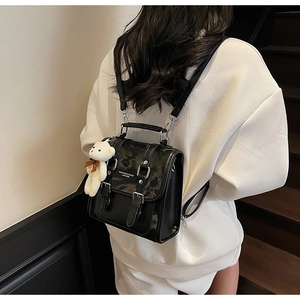 Detail of leather backpack featuring marble pattern flap and plush bear charm
