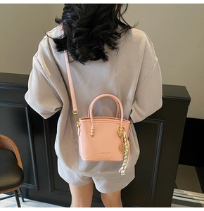 Detail view of pink bucket bag with gold tennis pendant and striped scarf accessory