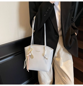 Dettaglio della borsa tote in pelle PU azzurra con logo MIKAXOQI e ciondolo a nappa