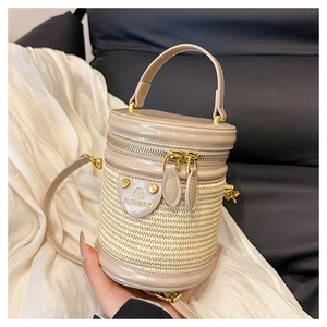 Dettaglio macro della borsa a cilindro intrecciata beige con finiture dorate lucide