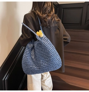 Détail d'un grand sac fourre-tout tressé bleu avec une tulipe sur la bandoulière