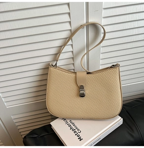 Detailed close-up of the beige woven texture and metallic clasp on the crossbody bag