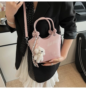 Sac seau rose avec texte en relief et breloque chiot en peluche porté dans un bureau