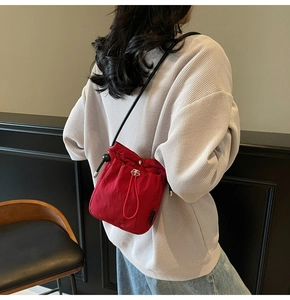 Detail of red drawstring bucket bag with black strap on model for stylish look