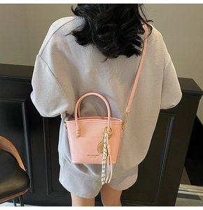 Detail of pink contrast bucket bag featuring tennis racket charm and striped silk scarf