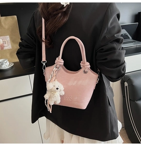 Détail du sac seau rose en cuir avec pendentif ours en peluche et foulard en soie rayé