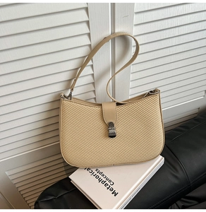 Close-up of beige woven shoulder bag featuring fine texture and leather strap detail