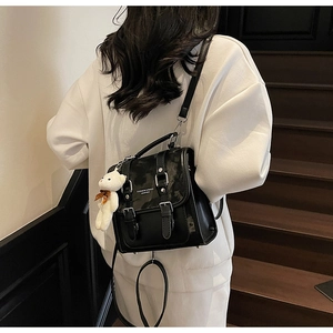 Detail of vintage black PU leather backpack with silver buckle and plush bear charm