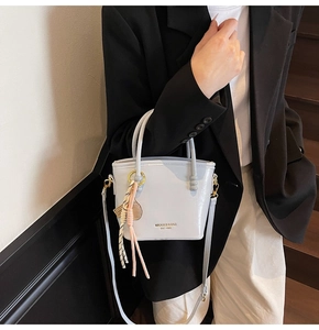 Detailed view of the color-block bucket bag with elegant scarf accessory on a model