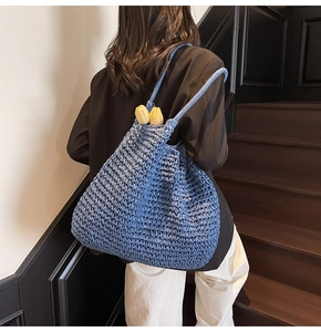 Détail de la texture d'un sac cabas bleu tissé à la main porté par un mannequin chic
