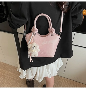 Vue détaillée du sac seau rose avec breloque chiot en peluche et ruban décoratif