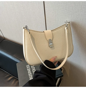Close-up of beige woven crescent bag featuring silver metal buckle and premium texture
