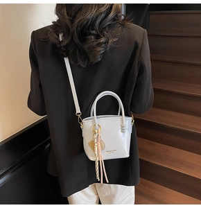 Close-up of a grey bucket bag with a decorative silk scarf and metal tennis racket charm