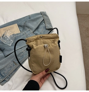 Detail view of the khaki crossbody bucket bag with drawstring closure and black cord strap