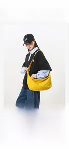 Close-up of bright yellow nylon crescent crossbody bag worn by a model on light gray background