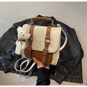 Detailed close-up of a color-block crossbody bag featuring a plush bear keychain charm