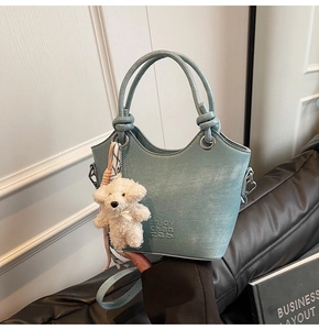 Détail du sac seau bleu clair avec poignée nouée et breloque ours en peluche blanc