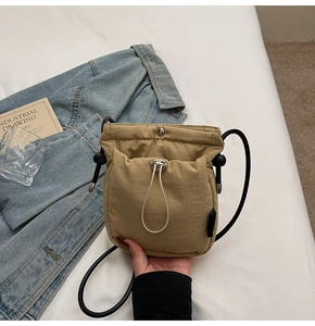 Detail of khaki nylon drawstring bucket bag with durable fabric and long thin shoulder strap