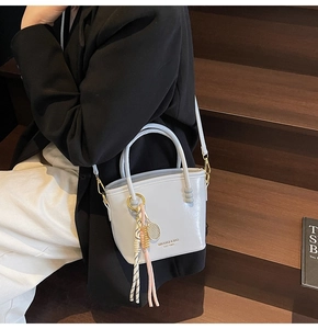 Detail of light blue leather bucket bag with metal ring charm and tennis racket pendant