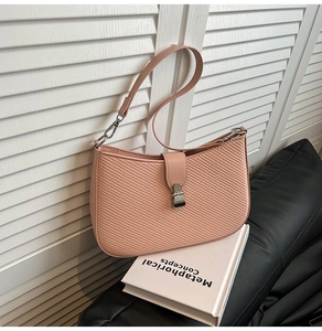 Close-up of pink shoulder bag with diagonal woven texture and metal clasp closure