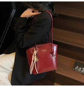 Dettaglio della borsa tote in pelle verniciata bordeaux con nappa e logo metallico