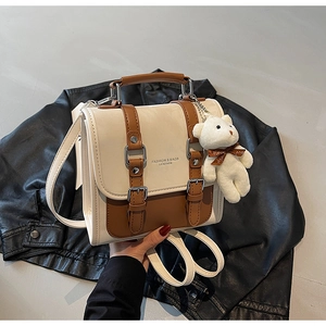 Detail of two-tone PU leather backpack with silver buckles and plush bear charm