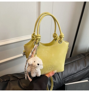 Détail d'un sac seau jaune clair montrant la texture du cuir et le charm de chien en peluche