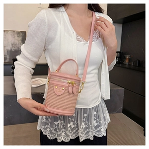 Borsa a secchiello cilindrica rosa in pelle intrecciata indossata da una modella