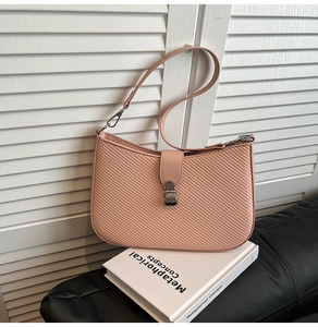 Detail view of the light coral pink woven shoulder bag with a silver metal clasp